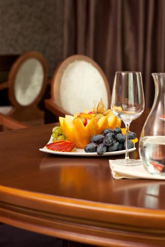 a plate of fruit on a table with a glass of wine at Budapest Hotel - Free Parking in Sofia