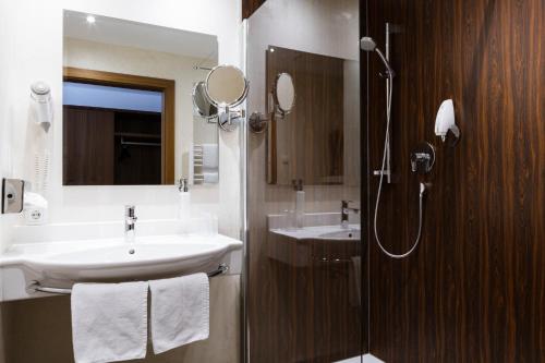 a bathroom with a sink and a shower and a mirror at Hotel Kapeller Innsbruck in Innsbruck