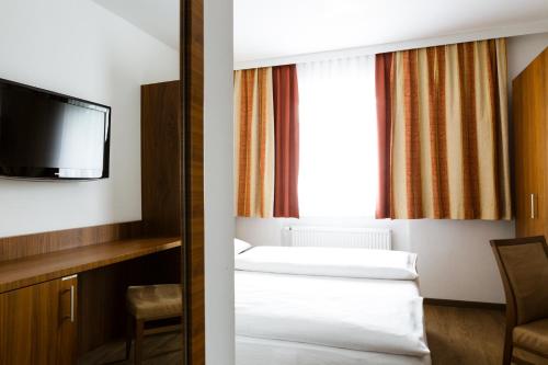 a hotel room with two beds and a tv at Hotel Kapeller Innsbruck in Innsbruck