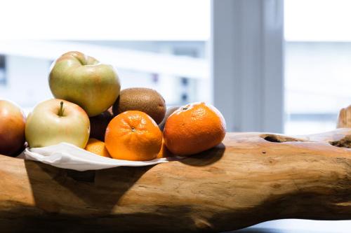 a bowl of fruit on a table with apples and oranges at Hotel Kapeller Innsbruck in Innsbruck