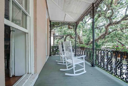two white chairs sitting on the porch of a house at Malaga Inn in Mobile