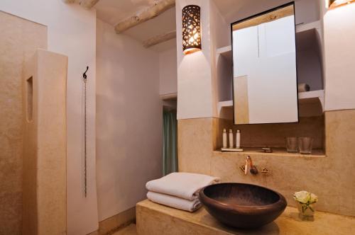 a bathroom with a wooden bowl sink and a mirror at Riad Dar Hanane in Marrakesh