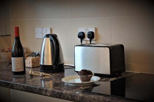 a counter with a microwave and a bottle of wine and a cupcake at Palmer's Apartment in Bristol