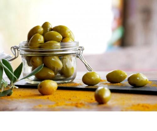 a jar filled with green olives on a table at Rumman Hotel in Madaba