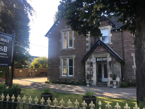 a brick house with a sign in front of it at Merlindale in Crieff