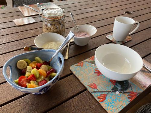 a bowl of fruit on a wooden table with two cups at Harbour View Retreat Mangonui in Mangonui