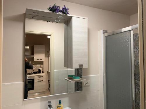 a bathroom mirror with a sink and a person in the kitchen at AL GELSOMINO in Pisa