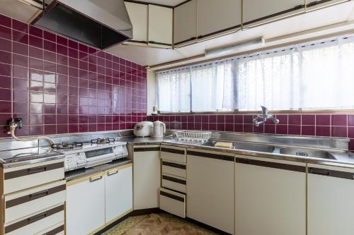 a kitchen with white cabinets and purple tiles at Shinjuku Japanese-style two storey house in Tokyo
