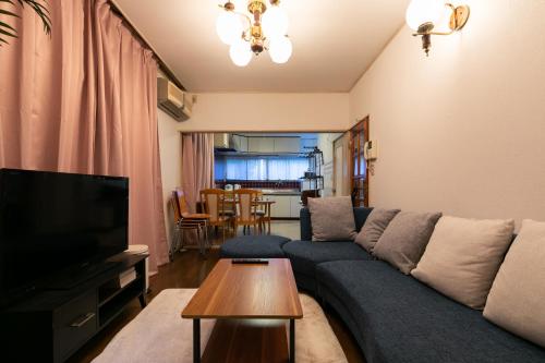 a living room with a blue couch and a tv at Shinjuku Japanese-style two storey house in Tokyo