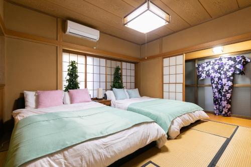 two beds sitting in a room with windows at Shinjuku Japanese-style two storey house in Tokyo