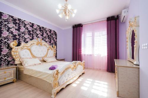 um quarto com uma cama com paredes roxas e um lustre em Razmestim в ЖК Шахристан на 15 этаже em Almaty