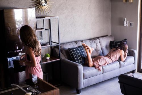 two girls standing in a living room with a woman laying on a couch at -Musée Villa- in Nakijin