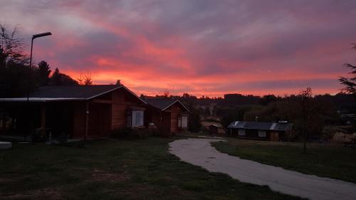 a sunset over a house with a dirt road at Turismo Jaos Cabañas Tinas y Quincho in Futrono