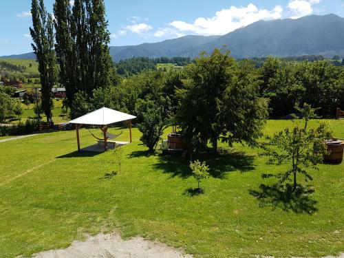 a picnic table with a white umbrella in a field at Turismo Jaos Cabañas Tinas y Quincho in Futrono