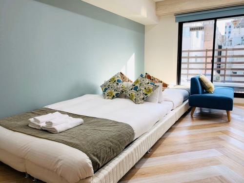 a bedroom with a large bed and a blue chair at WELLSTAY Honmachi in Osaka