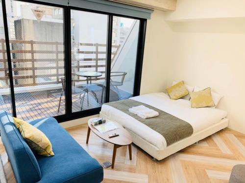 une chambre avec un lit et un canapé bleu dans l'établissement WELLSTAY Honmachi, à Osaka