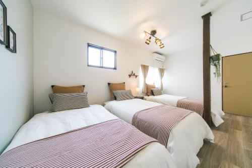 three beds in a room with white walls at Nao's House USJ 一軒家貸切 in Osaka