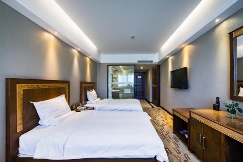 a hotel room with two beds and a television at Sun Moon Lake Hotel Dalian大连火车站店 in Dalian