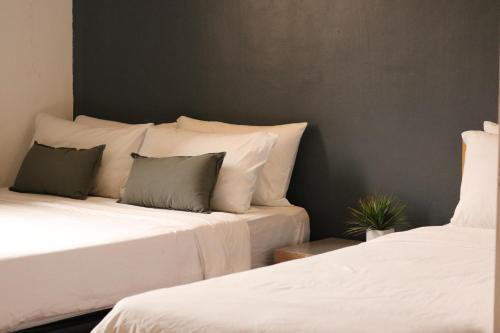 two beds with white sheets and green pillows in a room at IKO homes in Kota Kinabalu