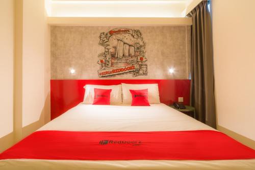 a bedroom with a red headboard and a white bed at RedDoorz at Geylang in Singapore