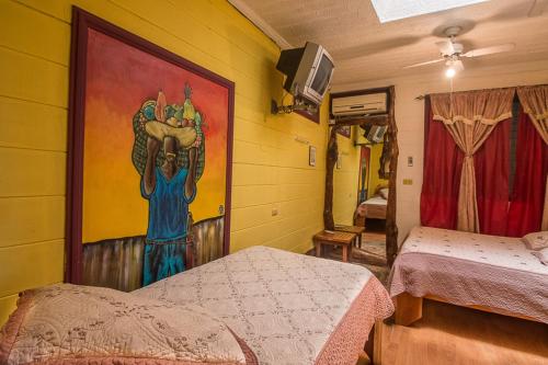a room with two beds and a painting on the wall at Casa Antigua Hotel in Alajuela City