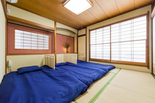 uma grande cama azul num quarto com duas grandes janelas em Tessen Guesthouse em Shizuoka