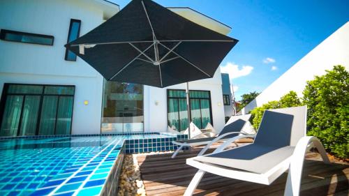 a pool with chairs and an umbrella next to a swimming pool at Happy Family Villa in Phuket Town