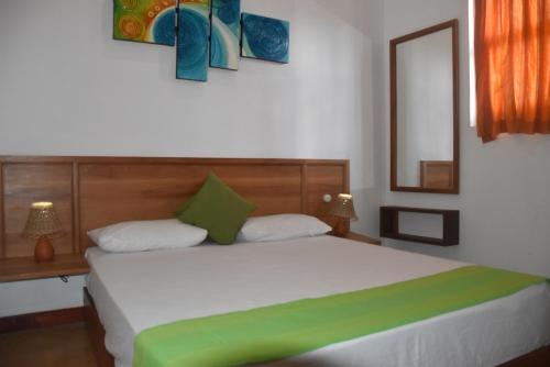 a bedroom with a large white bed with green pillows at Villa 61 in Ambepussa