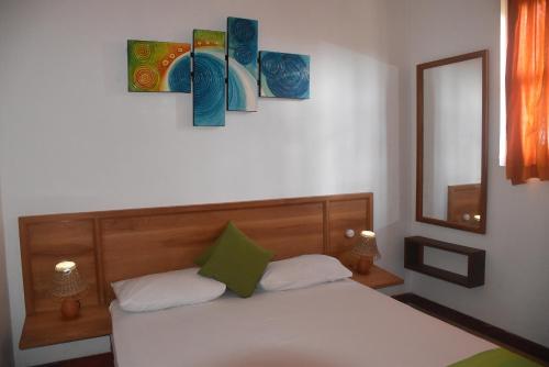 a bedroom with a bed with three paintings on the wall at Villa 61 in Ambepussa