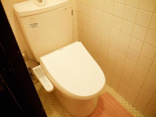 a white toilet in a bathroom with a remote control at Fukuoka Condominium in Fukuoka