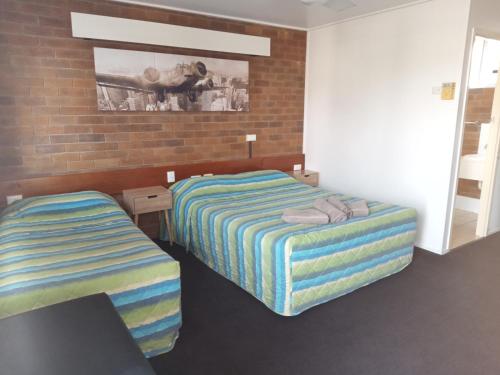 a bedroom with two beds and a brick wall at Millmerran Motel in Millmerran