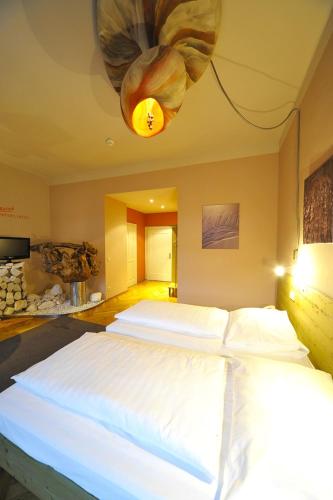 a bedroom with two beds and a chandelier at Erlebnis Post - Stadthotel mit EigenART in Spittal an der Drau
