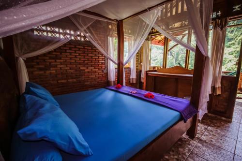 ein Schlafzimmer mit einem blauen Bett in einem Zelt in der Unterkunft Garden Inn in Bukit Lawang