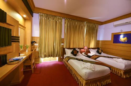 a hotel room with two beds and a desk at Shwe Kyun Hotel in Taunggyi