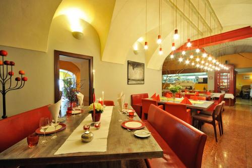 a dining room with a long table and red chairs at Erlebnis Post - Stadthotel mit EigenART in Spittal an der Drau