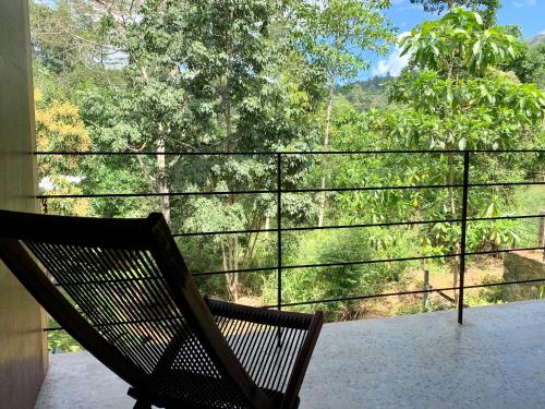 a bench sitting on a balcony looking out at the trees at Sati Villa Kandy Sri Lanka in Kandy