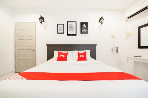a bedroom with a white bed with red pillows at Super OYO 89486 Kulim Inn in Kulim