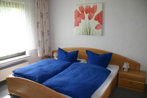 Un dormitorio con una cama con almohadas azules y una pintura en Apartmenthaus Solino, en Willingen