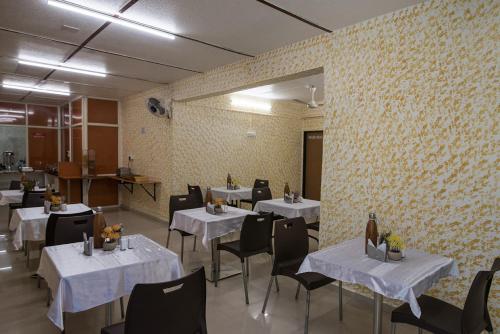 een eetkamer met witte tafels en zwarte stoelen bij Hotel Sheetal Plaza in Surat