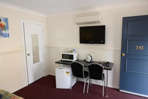 a room with a table with a microwave and a blue door at Lithgow Motor Inn in Lithgow