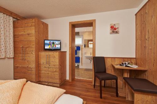 a room with a bed and a desk with a television at Gästehaus Falkner Ignaz in Sölden