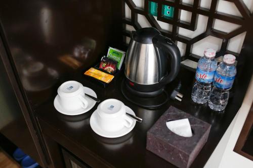 una cafetera y tazas en un mostrador con botellas de agua en Bảo Hân 2 Hotel, en Ha Long