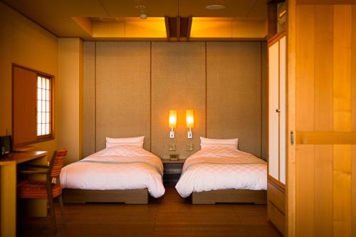 a bedroom with two beds and a table and a desk at Migiwaya in Yaizu