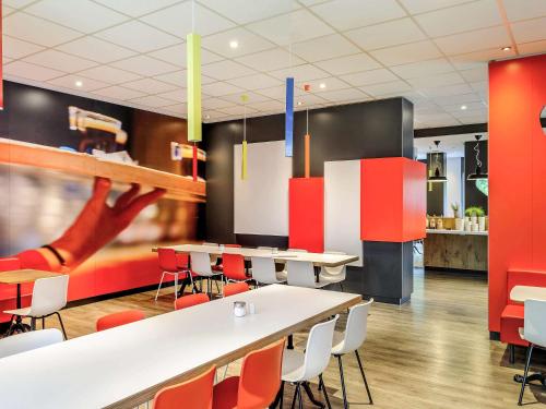 a cafeteria with tables and chairs and a slide at ibis Hotel Frankfurt Airport in Kelsterbach