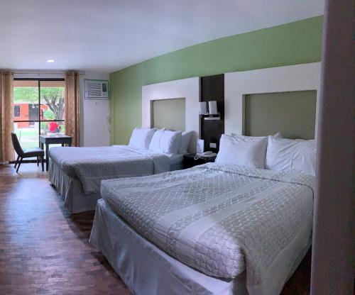 a hotel room with two beds and a table with a chair at Maharajah Hotel in Angeles