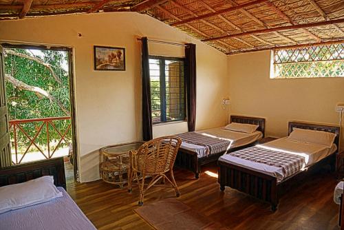 a room with three beds and a table and chairs at Nature Care Village Farmstay- Rajaji National Park in Rishīkesh
