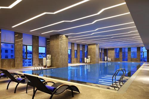 ein großer Pool in einem Gebäude mit Stühlen in der Unterkunft Wanda Realm Hotel Dongying in Dongying