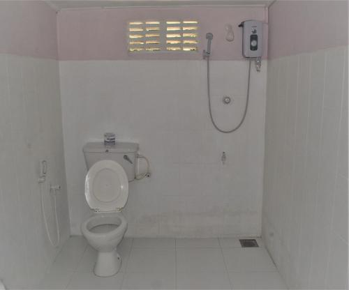 y baño blanco con aseo y ducha. en Deniyaya Guest House, en Deniyaya