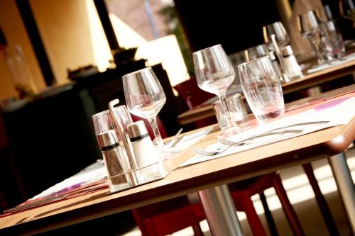 a table with wine glasses and silverware on it at Campanile NATURE - Cergy Saint Christophe in Cergy