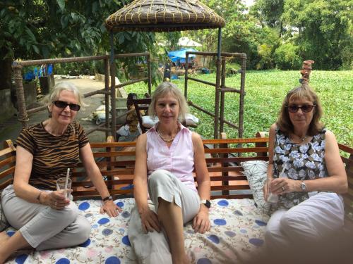 three women sitting on a bench in a park at Thara's Houseboat in Alleppey